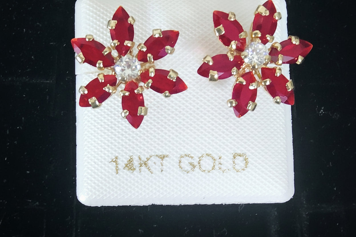 Red flower-shaped earrings on a 14K gold card against a black background