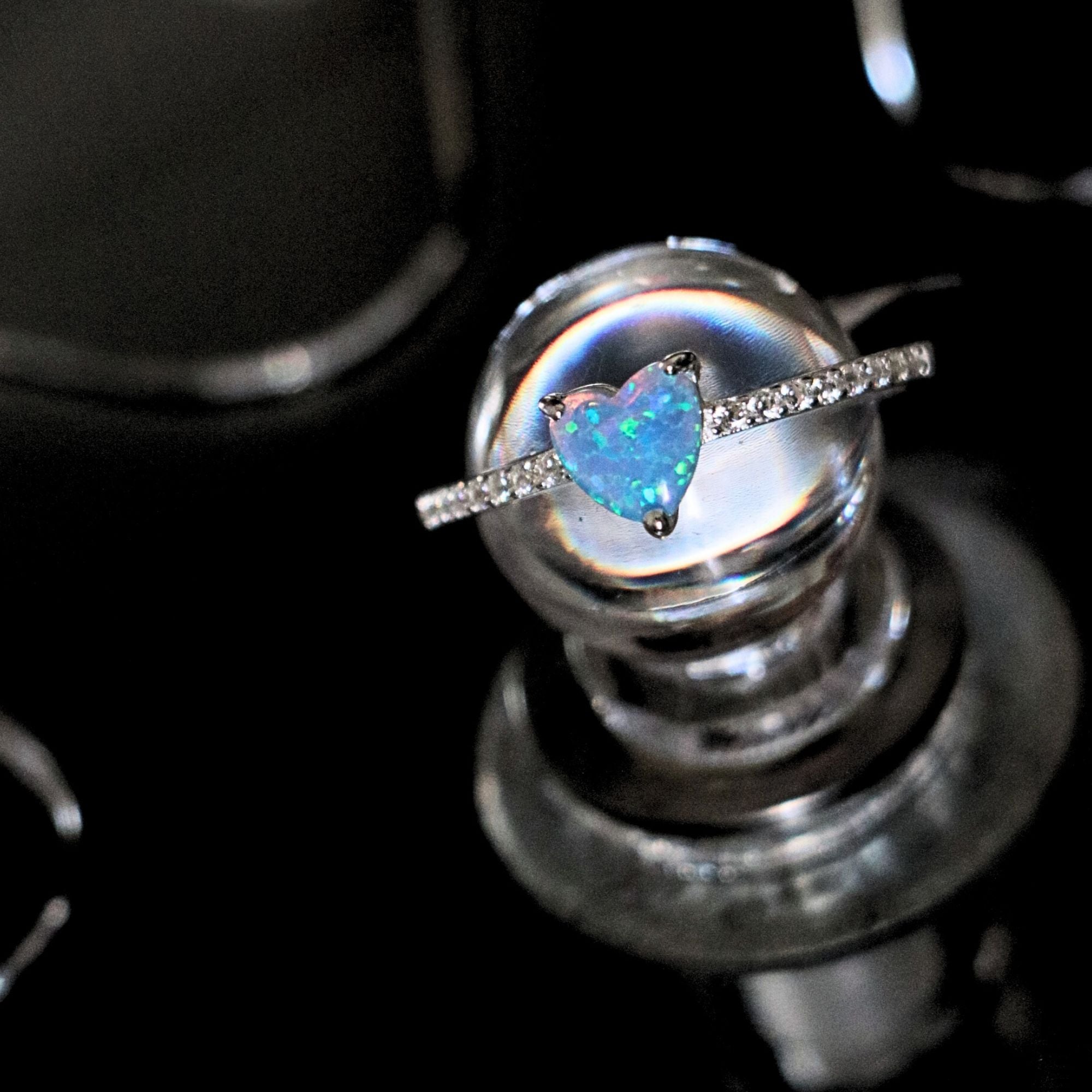 Heart-shaped opal ring with diamond band on a dark background